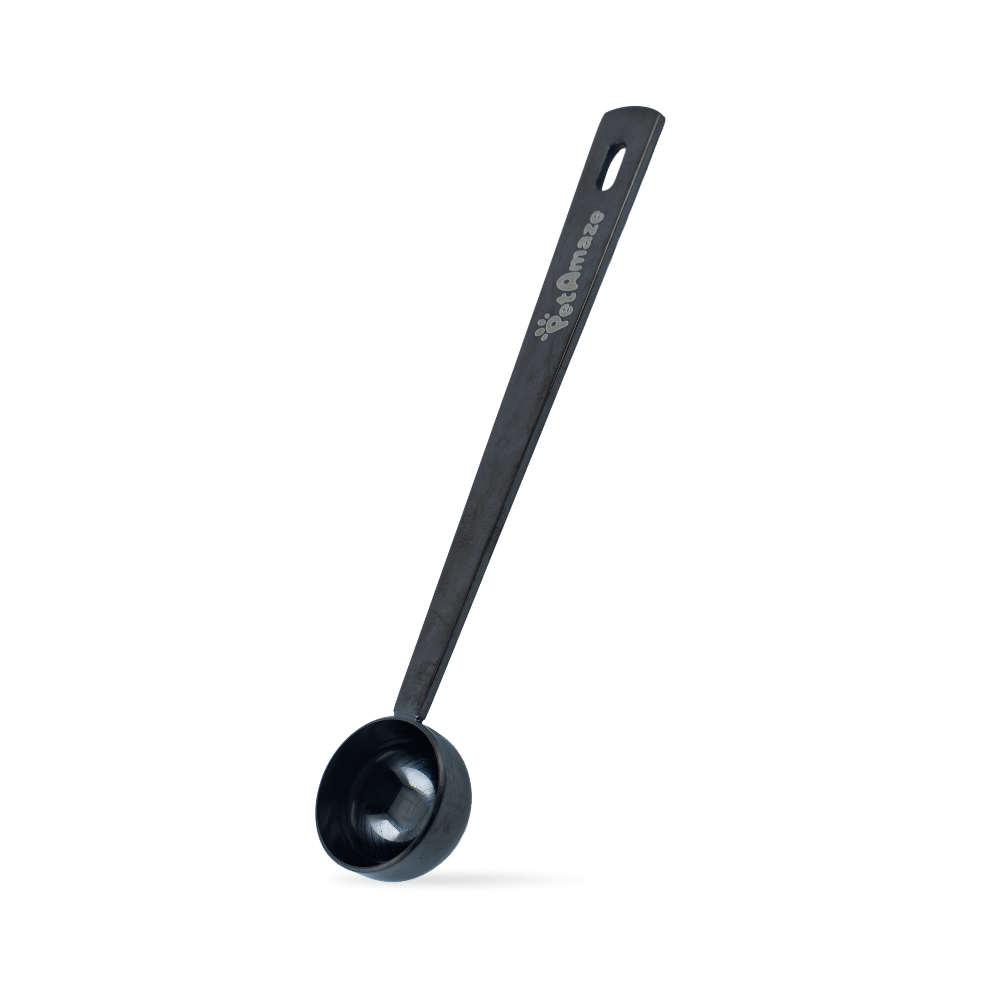 Black stainless steel PetAmaze measuring scoop on a white background