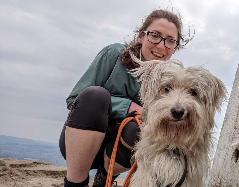 Woman with glasses and a dog on a mountain trail